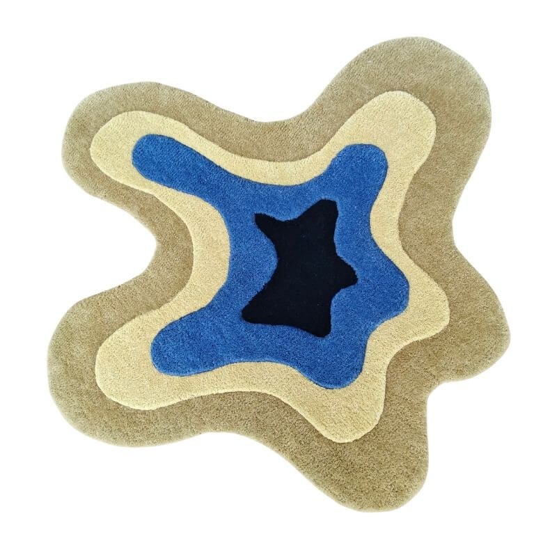 FiRugs Auraline luxury hand-tufted rug featuring an odd, uneven, and unusual irregular puddle shape with concentric topographic wavy layers in sand beige, cream, cobalt blue, and a black center, hand-tufted in Varanasi, India from 100 percent New Zealand wool.